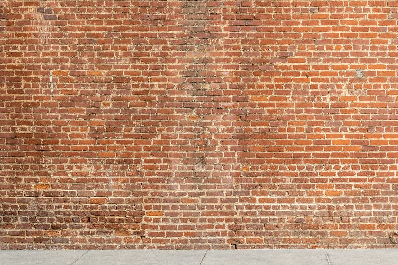 services-01 Detailed image of a textured red brick wall with a concrete base, ideal for architectural and design backgrounds.
